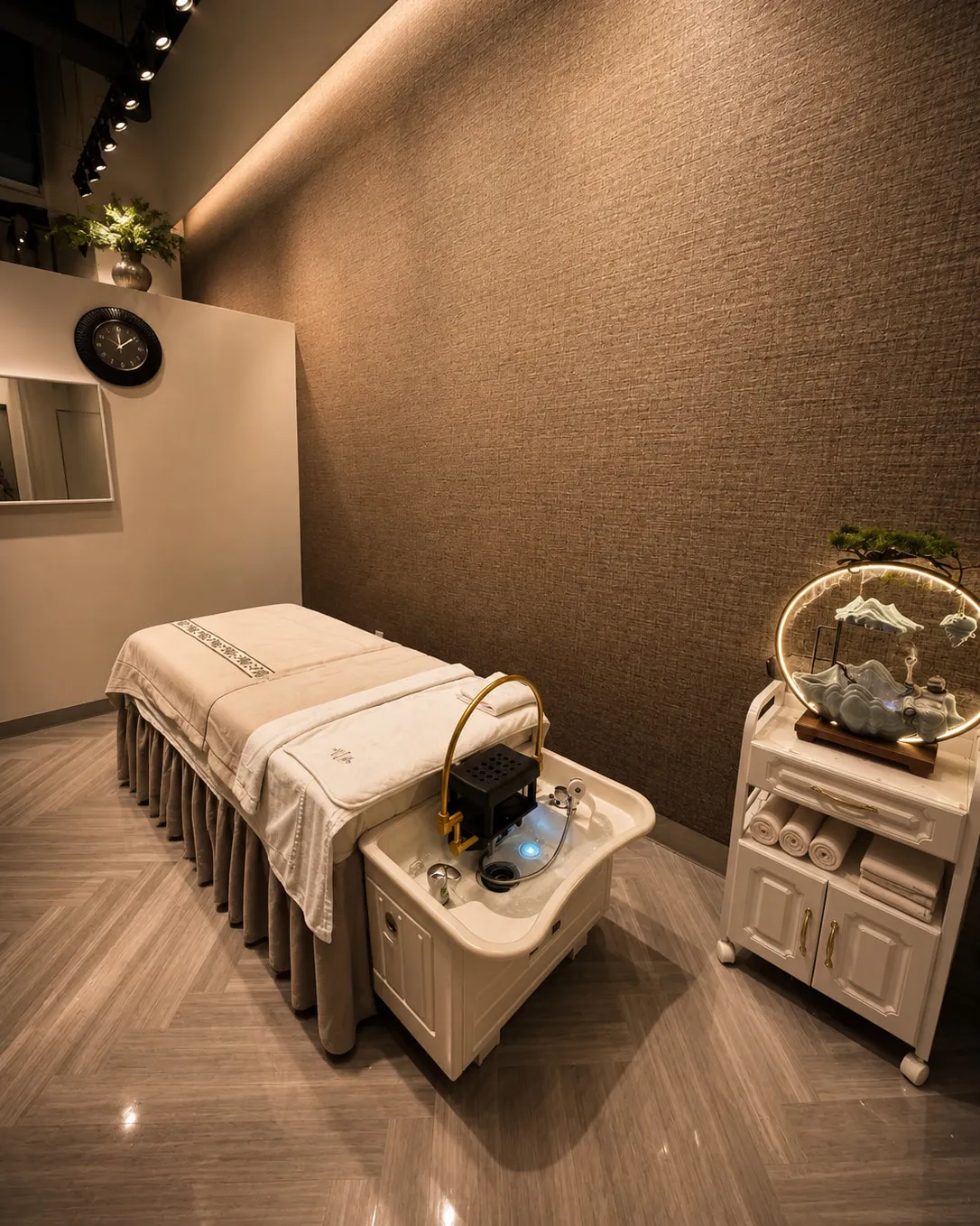 Made-up treatment bed under warm cove lighting in a private room at Pacific Massage & Head Spa, Redmond, WA, with folded towels on a trolley alongside